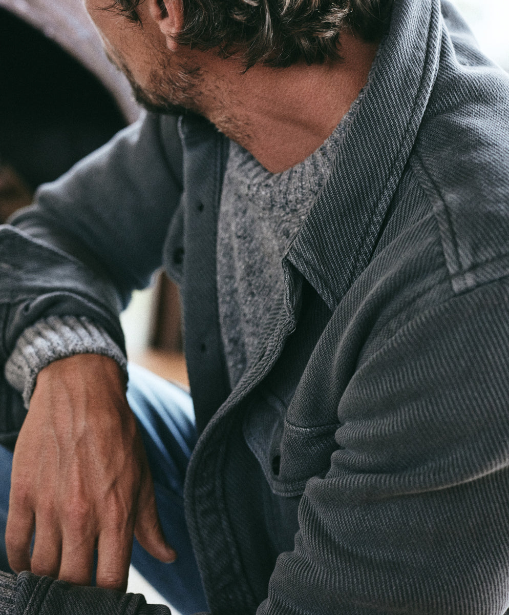 Outerknown sustainable apparel collection: man in gray denim-style jacket over knit sweater.