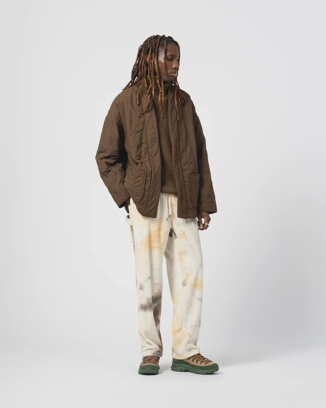 Casual model wearing Shorts & Pants For Everyday Comfort And Style: brown quilted jacket and tie-dye pants.