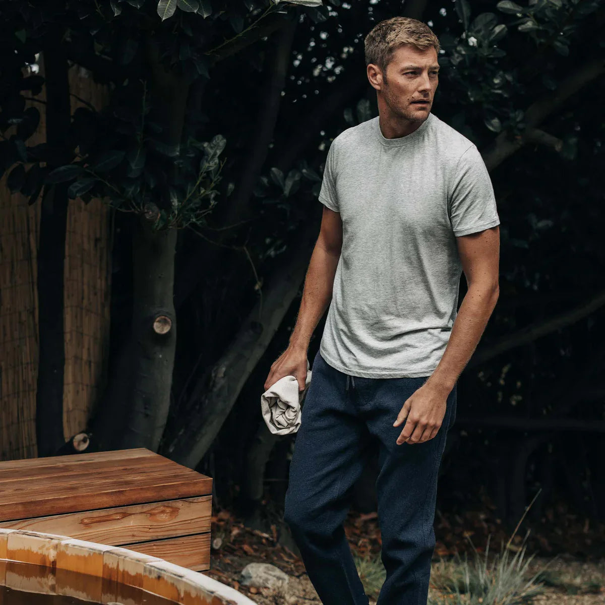 Man wearing a light gray T-shirt and navy pants from Taylor Stitch Classic Menswear Collection, outdoors.