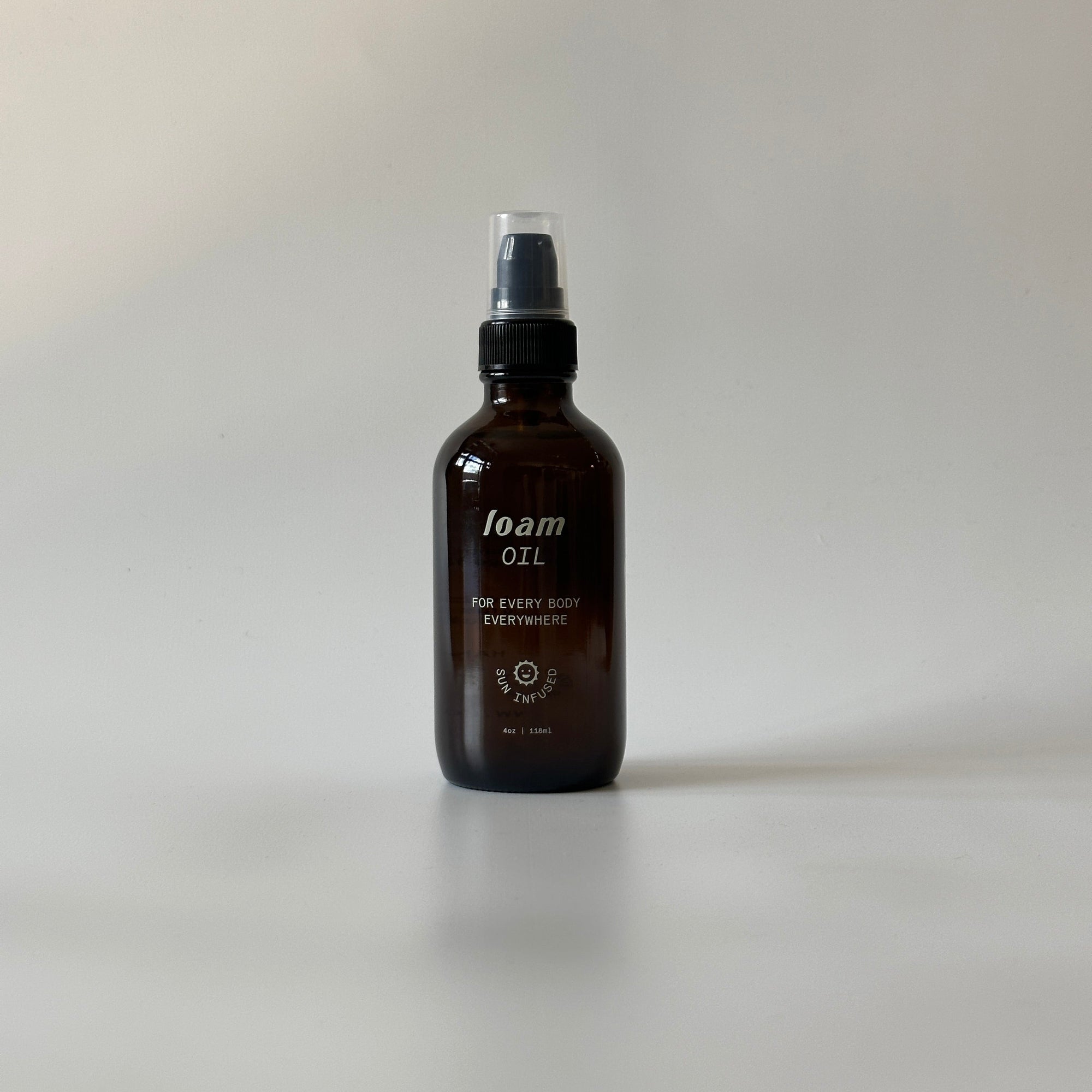 Loam Oil spray bottle in amber glass for skincare and grooming on white surface.