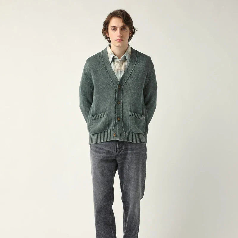 A man wearing a green cardigan with a grey backdrop - Above Snakes in Old Town Albuquerque