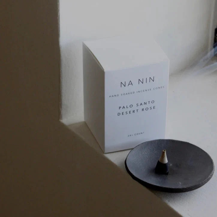 Na Nin Palo Santo Desert Rose incense cones beside a black burner, wellness-inspired fragrance.