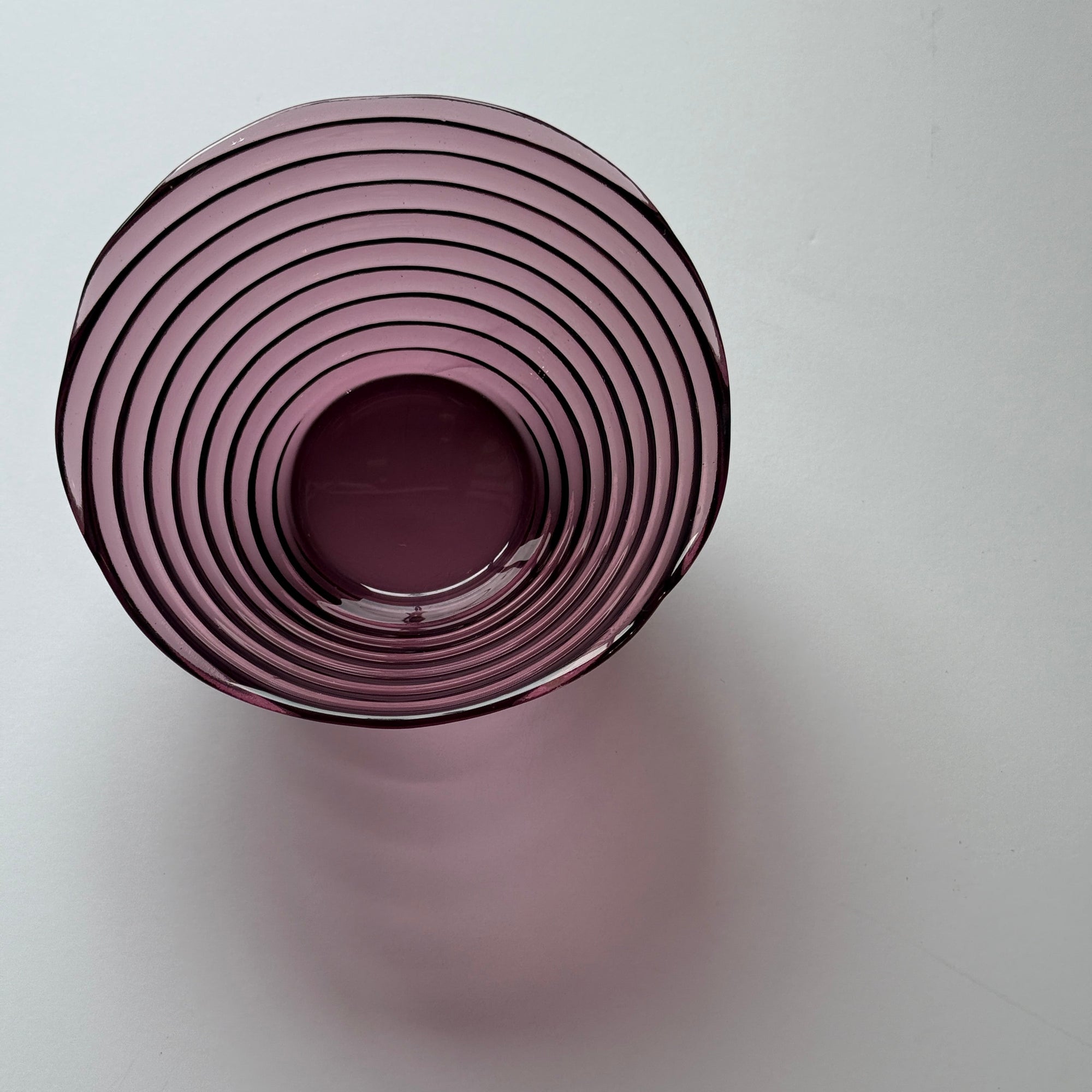 Top view of a purple glass vase with concentric circular design on a white background
